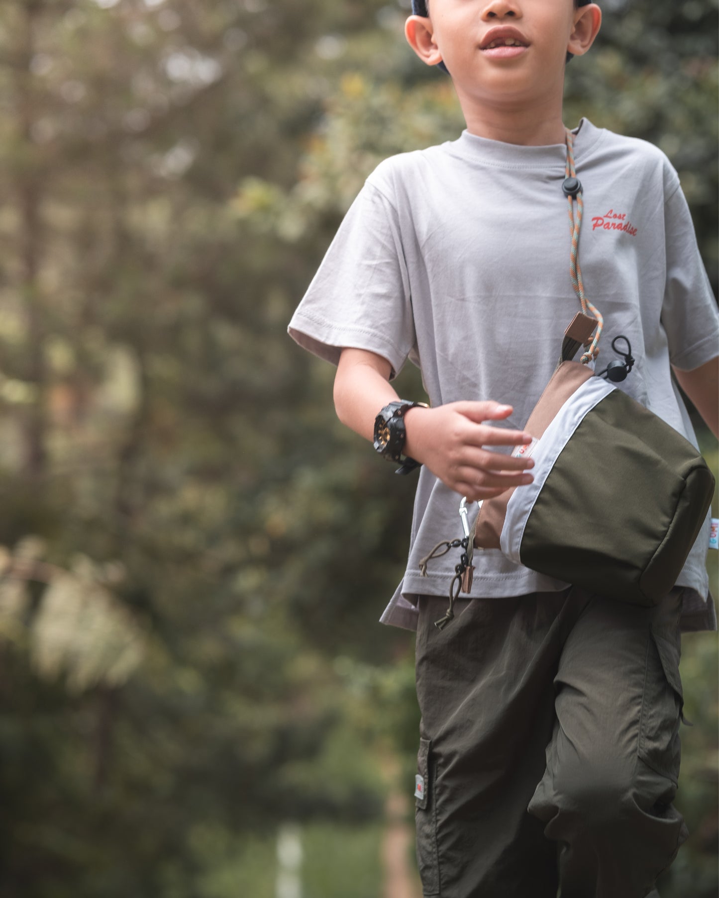 Close-up of a boy walking confidently with the PIXIES Nutty Sprout bag slung over his shoulder. The bag's stylish design and adjustable strap showcase its suitability for active kids.