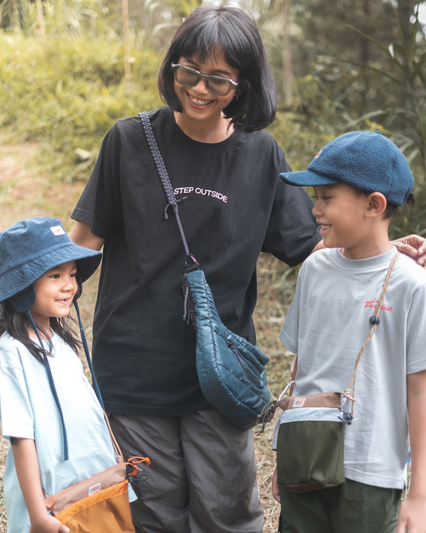 A family enjoying a day outside, with kids carrying various PIXIES Nutty Sprout bags, perfect for playful adventures.