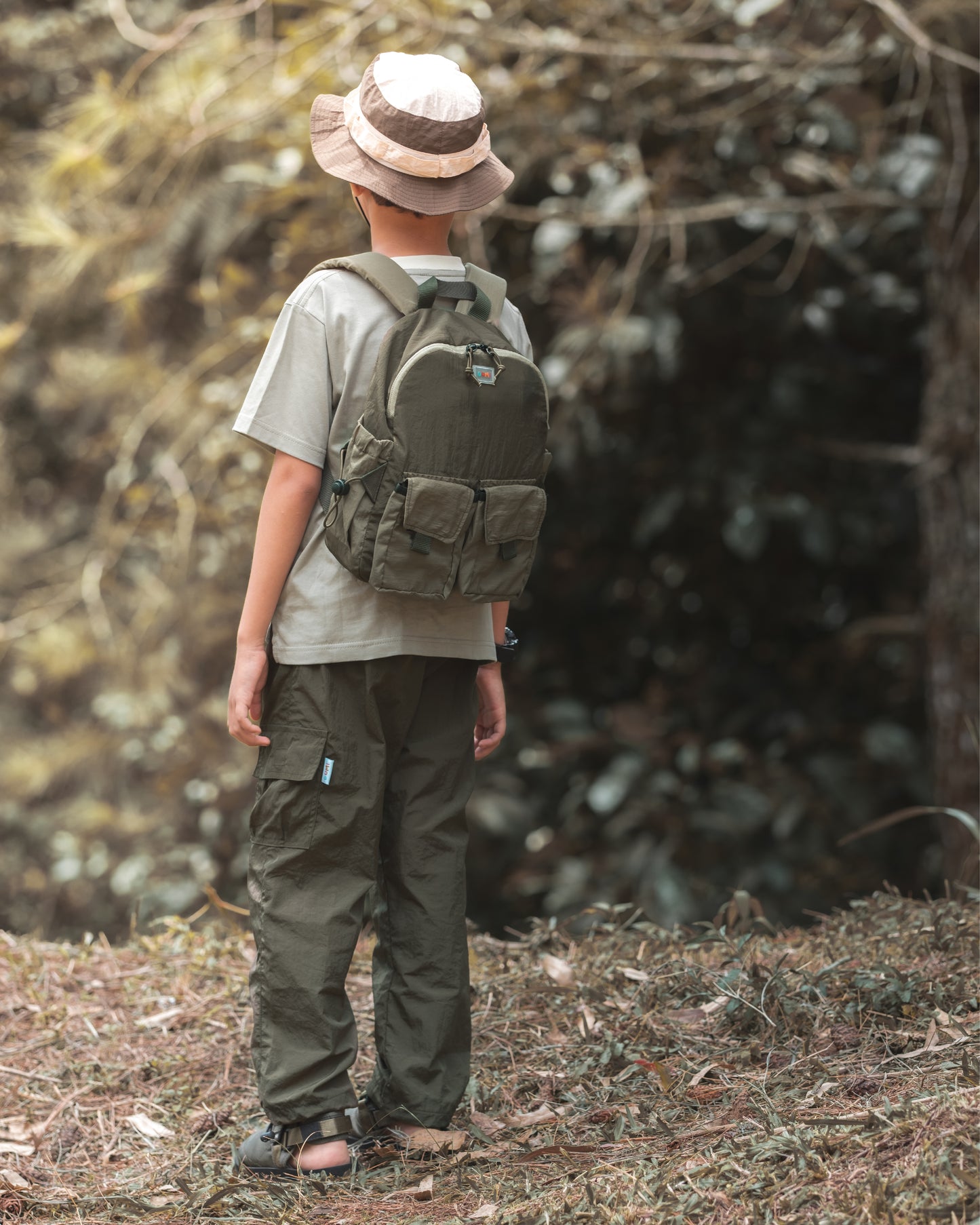 Back view of a child wearing the VENEX Dewy Drip Mini Backpack for Kids, capturing the backpack's storage and design while strolling through a peaceful forest.