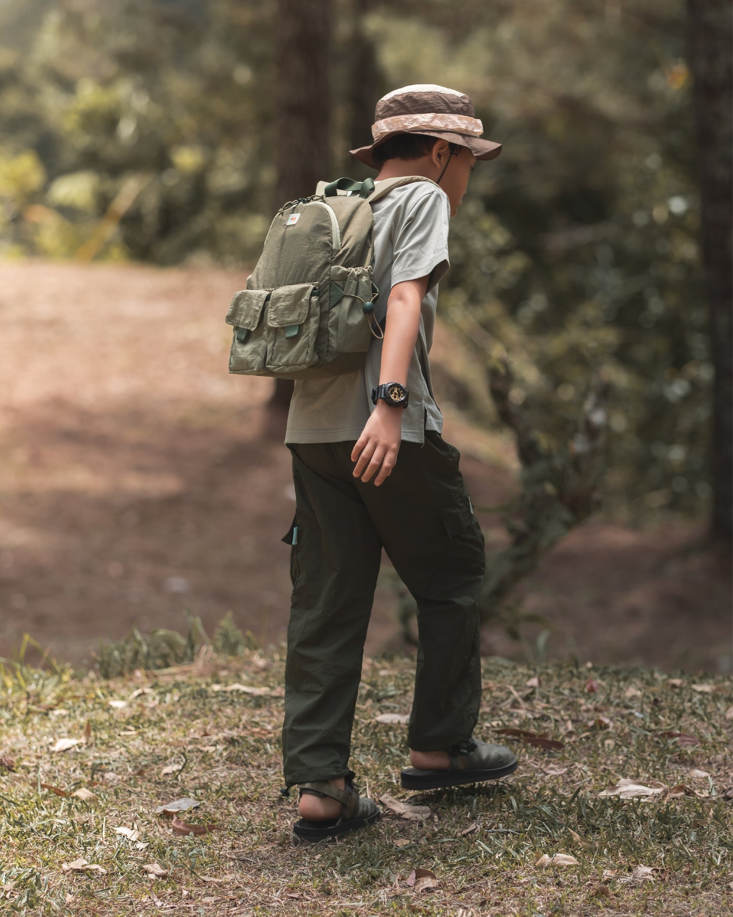 Child walking through the woods with the VENEX Dewy Drip Mini Backpack for Kids, dressed in practical attire, emphasising comfort and style for outdoor adventures.