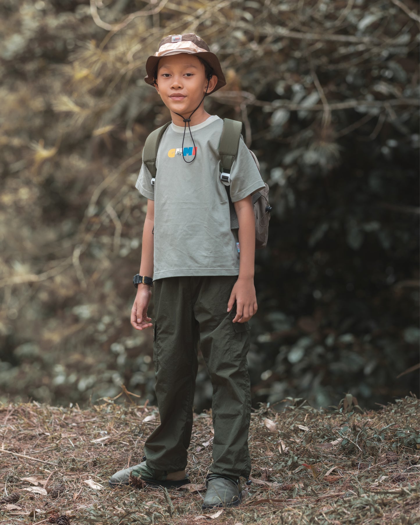 Happy child joyfully throwing dirt while wearing the VENEX Dewy Drip Mini Backpack for Kids, showcasing its playful and adventurous spirit in an outdoor setting.