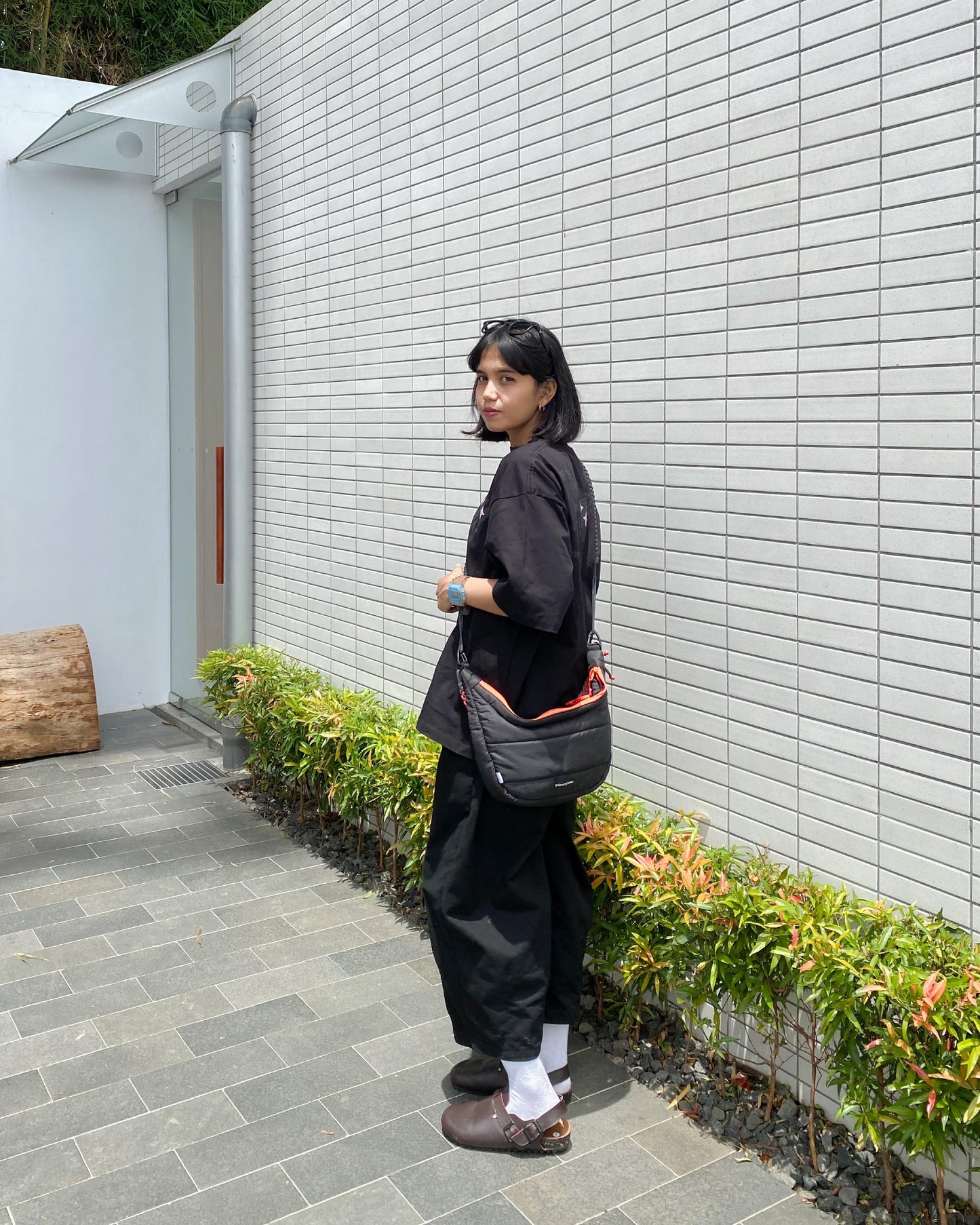 Side view of a woman with the QUITAN Abyss Padded Crossbody Bag, highlighting its trendy look and functional design.